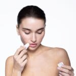 Eine Dame trägt den Mesoestetic mesoprotech Sun Stick 100 SPF 50+ auf ihr Gesicht auf, für intensiven Sonnenschutz.