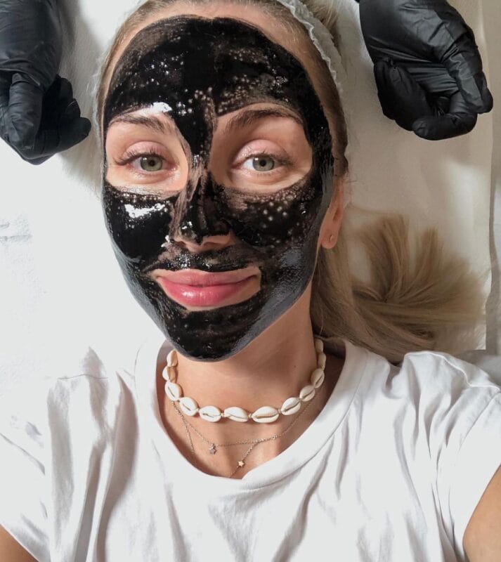 Frau mit V Carbon Peeling Gesichtsmaske und schwarzer Aktivkohle-Behandlung, während der Anwendung bei Mel’s Beauty & Academy.
